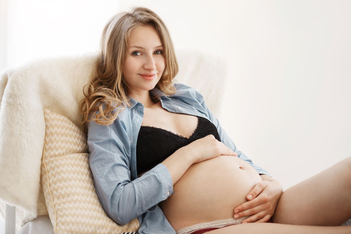 spokojená těhotná relaxující mladá žena v posteli